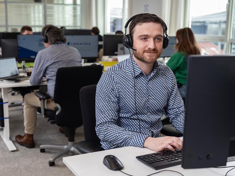 IT medewerker met headset achter pc